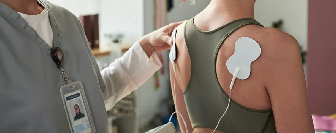 Specialist medical care utilizeaza un dispozitiv tens pentru tratamentul durerilor musculare si imbunatatirea recuperarii fizice