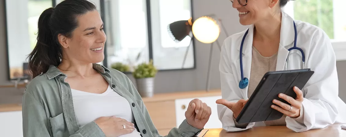 Femeie insarcinata aflata in cabinetul medicului, in timpul unei consultatii prenatale de rutina