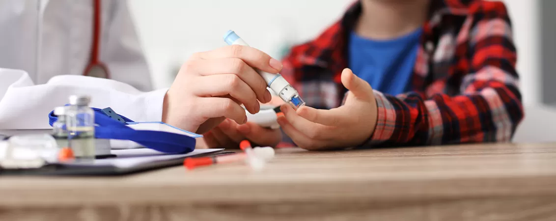 Medic recolteaza o proba de sange de la un copil diabetic pentru testarea glicemiei si monitorizarea sanatatii