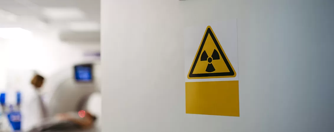Aparat CT in functiune, in spatele unui semn de avertizare pentru radiatii.