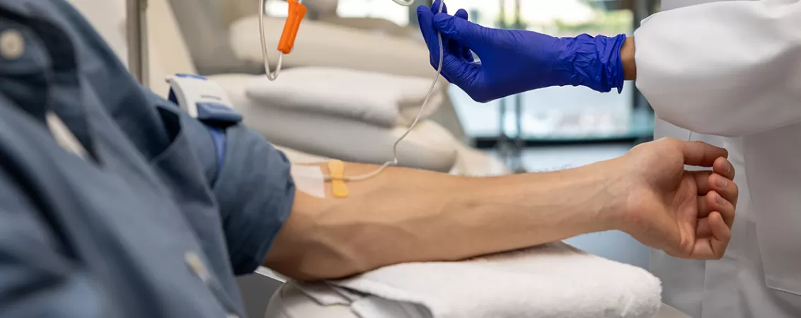 Barbat pacient care primeste o perfuzie intravenoasa in spital, ilustrand ingrijirea medicala
