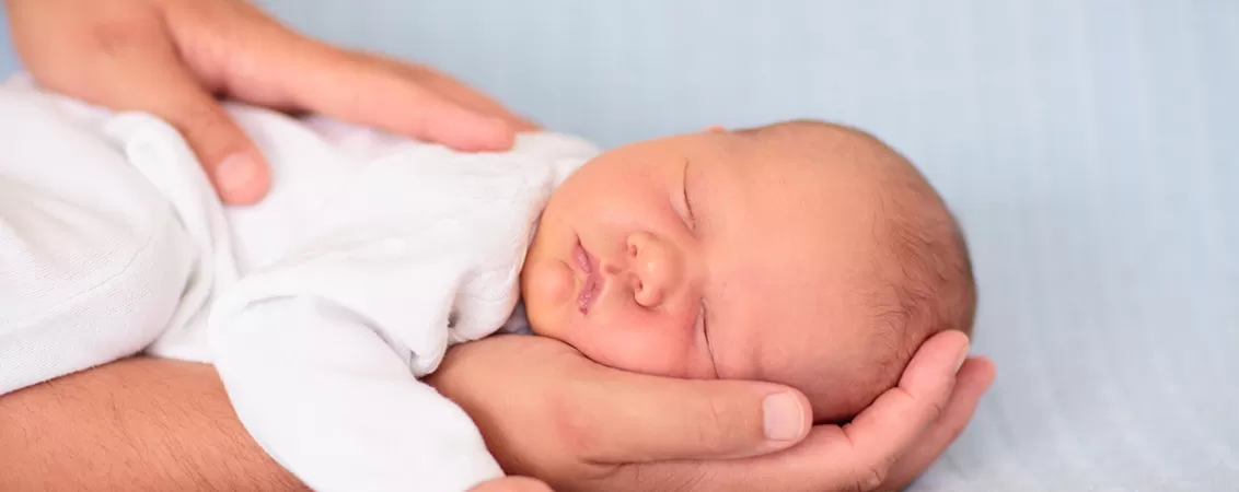 Bebelus nou nascut de sex masculin intins in pat, ilustrand primele momente de viata si ingrijirea noului nascut