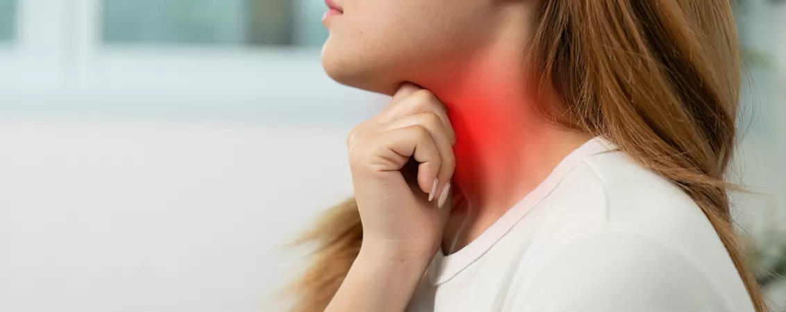 Femeie care isi atinge gatul si resimte durere in zona gatului, simptom asociat cu infectii respiratorii sau afectiuni ORL