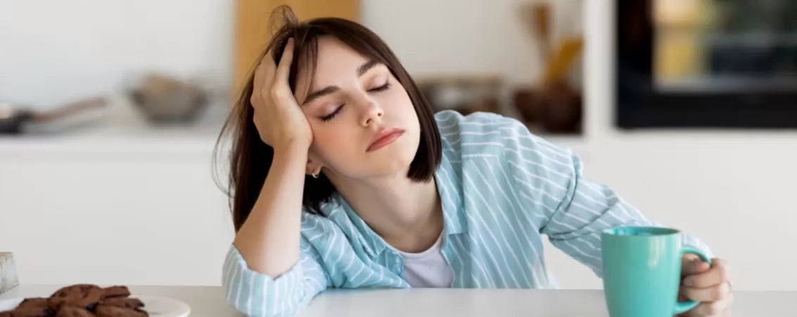 Femeie foarte obosita, cu o cana de cafea in mana