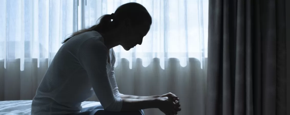 Femeie in depresie stand pe marginea patului
