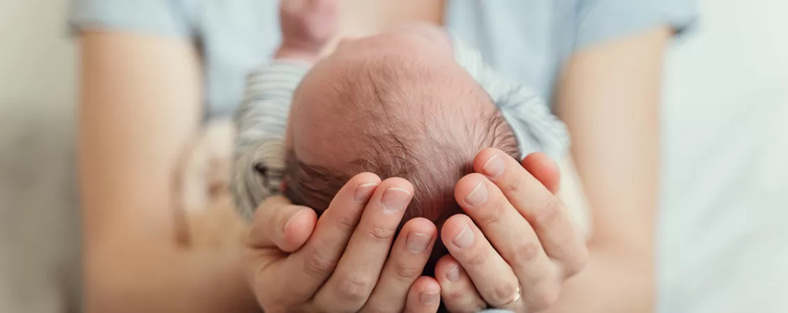 Mainile mamei care ingrijesc un nou nascut, simbolizand legatura dintre mama si copil imediat dupa nastere