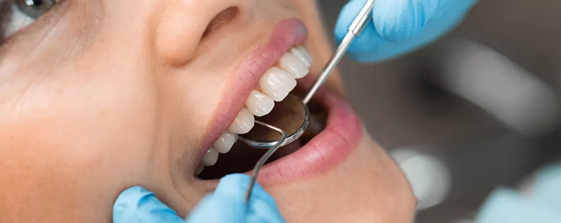 Prim plan cu zambetul unei fete in timpul unui consult stomatologic realizat de medicul dentist, evidentiind sanatatea dintilor si importanta controalelor stomatologice regulate.