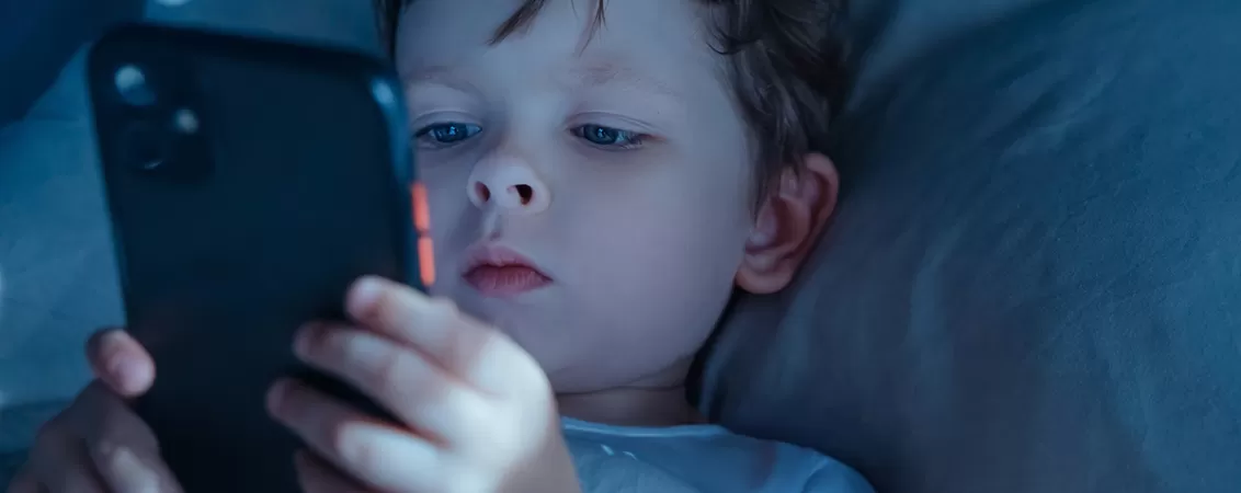 Copil mic cu telefon in maini, stand in pat.