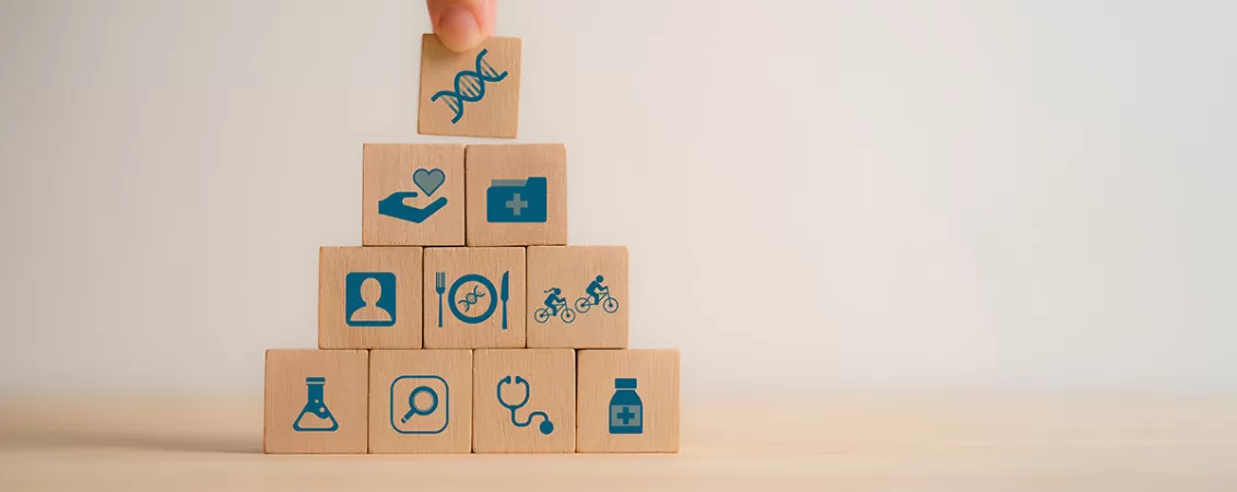 Cuburi din lemn cu diverse simboluri pentru a ilustra influenta geneticii in preventie si stil de viata adaptat fiecarei persoane.