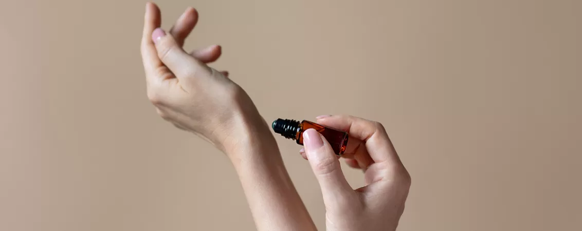 Femeie aplicand ulei de parfum pe mana