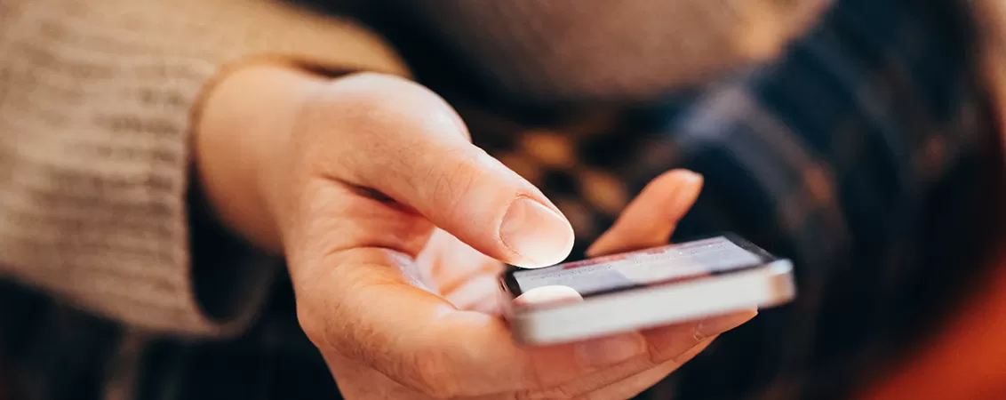 Femeie verificandu-si compulsiv notificarile pe telefon, ca semn al sindromului FOMO