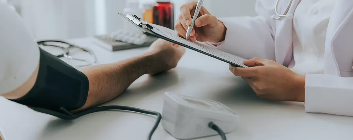 Medic examinand pacient cu hipertensiune in cabinet.