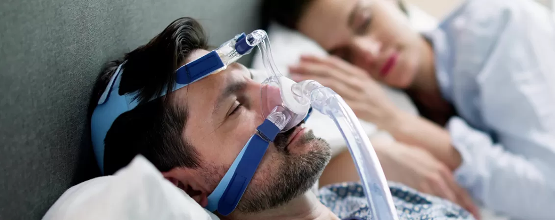 Barbat purtand aparat CPAP pentru apnee in somn