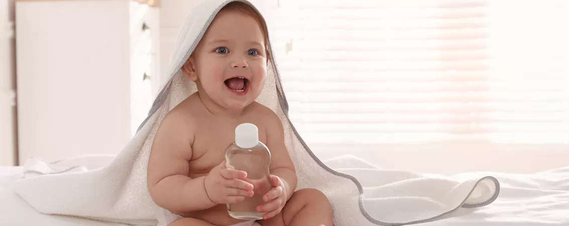 Bebelus cu o sticla de ulei pentru bebelusi in maini