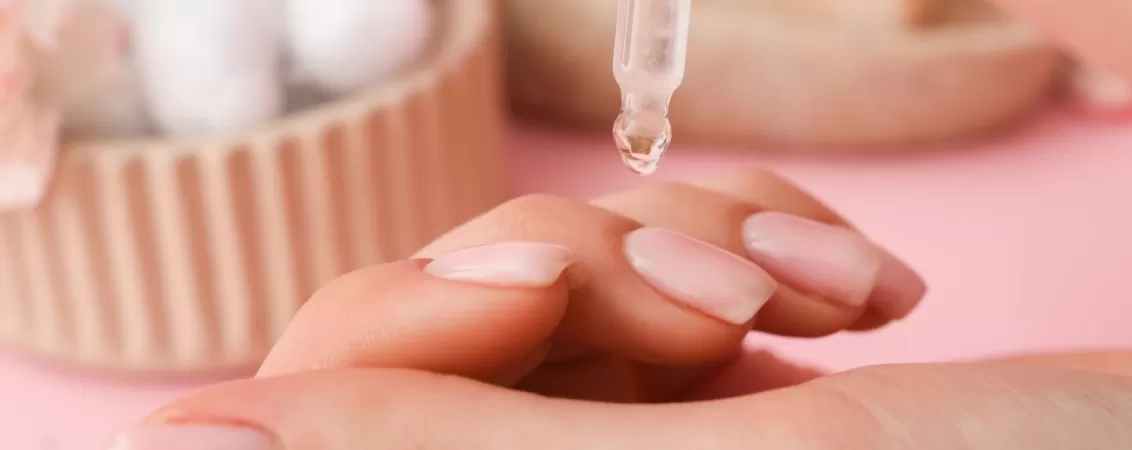 Femeie aplicand ulei de cuticule la unghiile de la maini