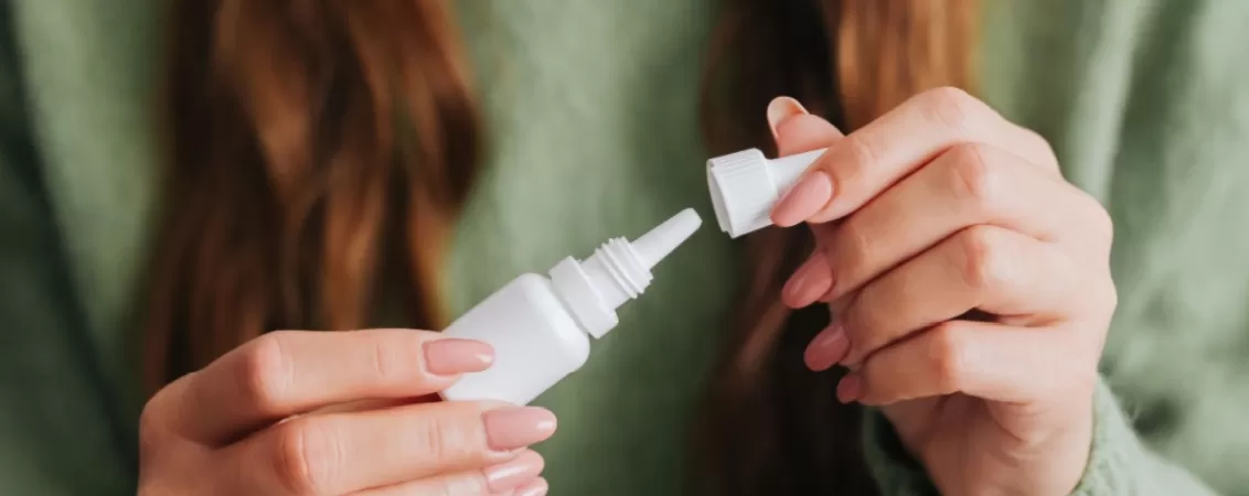 Femeie tinand in maini o sticluta cu picaturi ochi