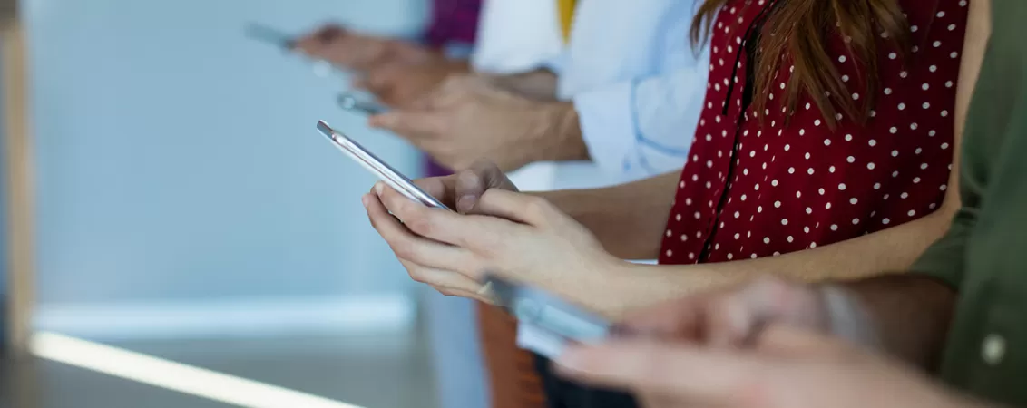 Grup de prieteni utilizand telefoanele in timp ce asteapta sa inceapa o sedinta