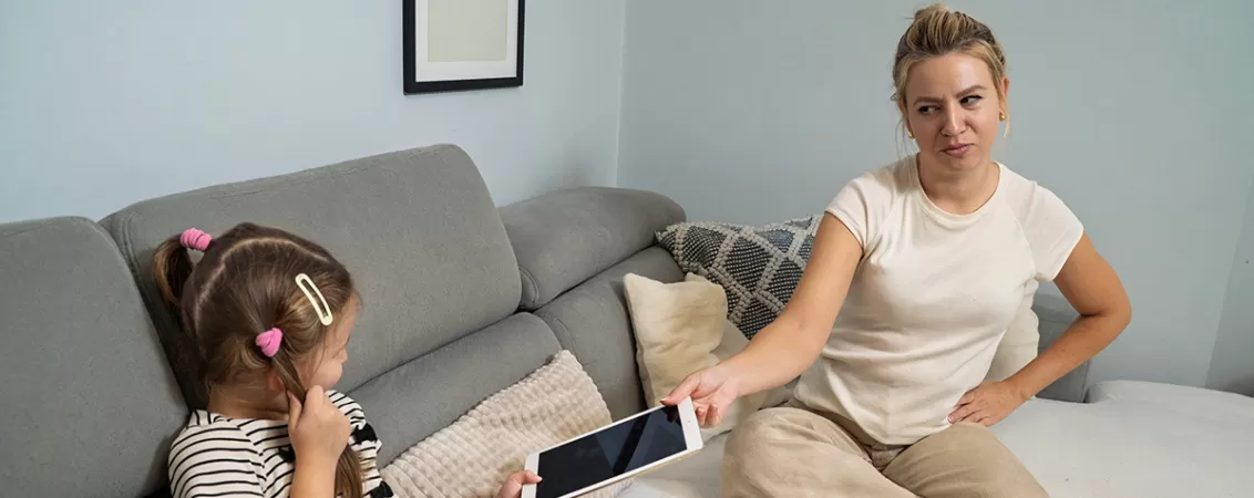 Mama care ii ofera inapoi fiicei sale o tableta, ilustrand utilizarea controlata a dispozitivelor digitale si implicarea parintilor in educatia copiilor