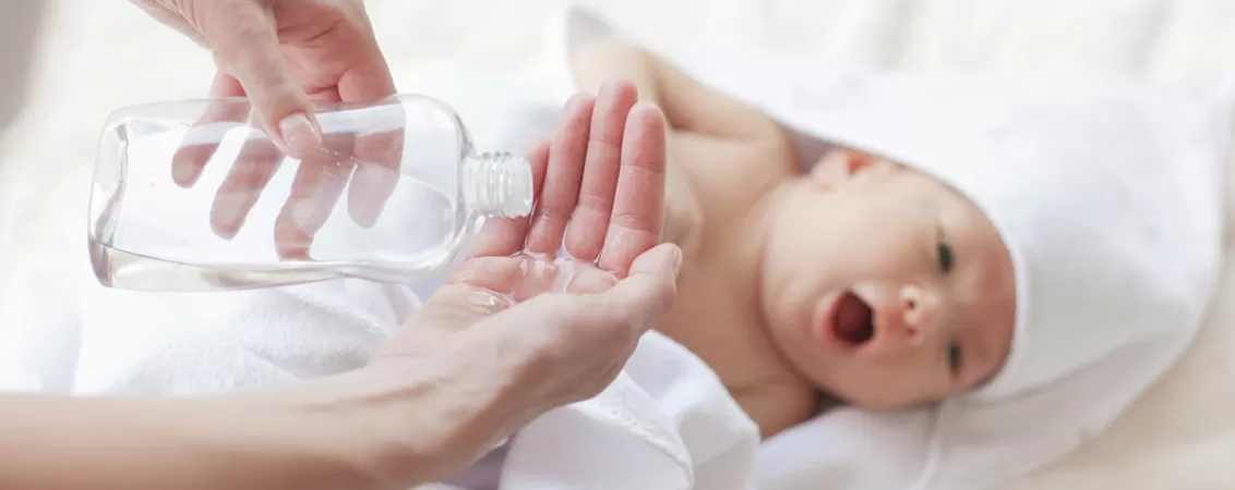 Mama folosind ulei de bebelusi pentru masaj dupa baita copilului