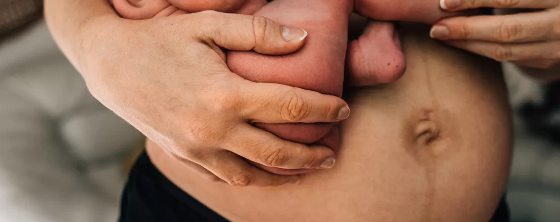 Mama in perioada de lehuzie tinandu-si bebelusul in brate