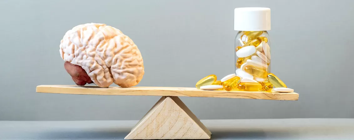 Model al creierului uman si suplimente pentru sustinerea functiei cerebrale asezate pe un cantar de echilibru, ilustrand conceptul de echilibru intre nutritie si sanatatea creierului.