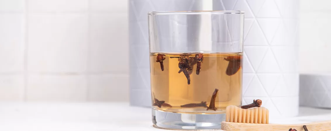 Pahar cu apa cu ulei de cuișoare si muguri de cuișoare
