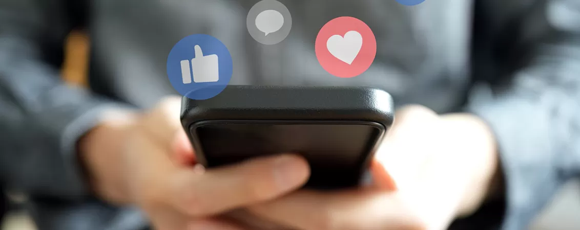 Persoana care tine un telefon in maini si verifica aplicatiile de social media