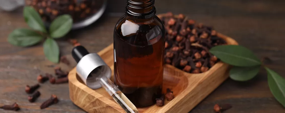 Sticluta cu ulei de esential de cuisoare, langa muguri uscati de cuisoare.