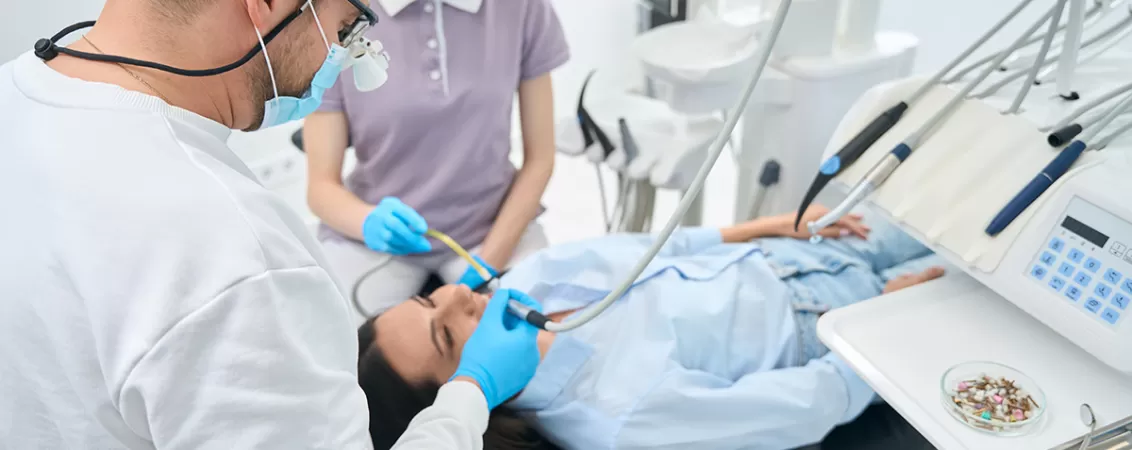 Stomatolog efectuand o opturatie de canal in cabinetul dentar, ilustrand tratamentele stomatologice si ingrijirea profesionala a sanatatii orale.