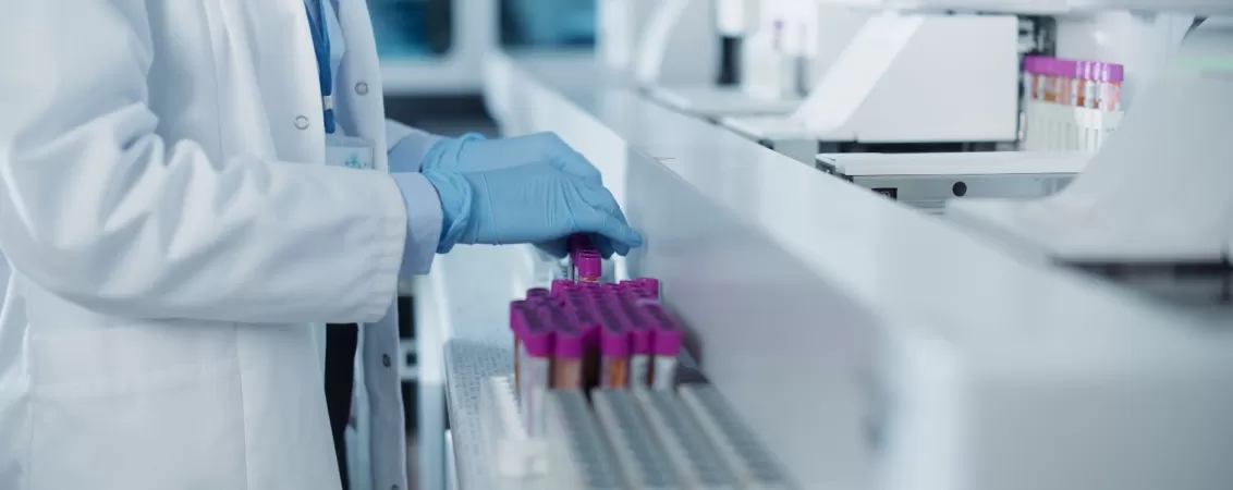 Tehnician de laborator in halat alb analizeaza probe de sange in mediu medical steril