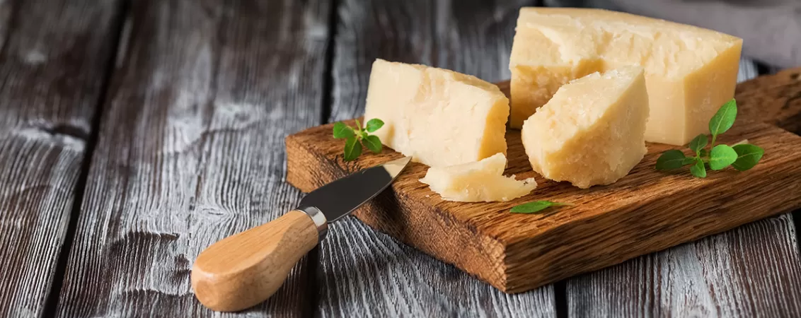 Bucati de parmezan pe un tocator din lemn