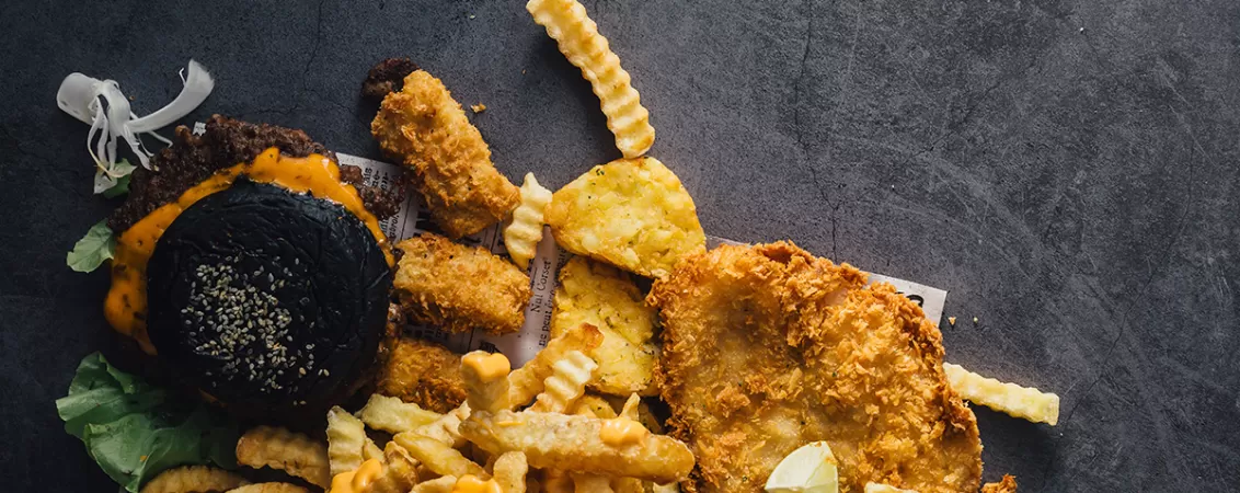 Burger fast food cu cartofi prajiti si sosuri, ilustrand alimente nesanatoase tip junk food