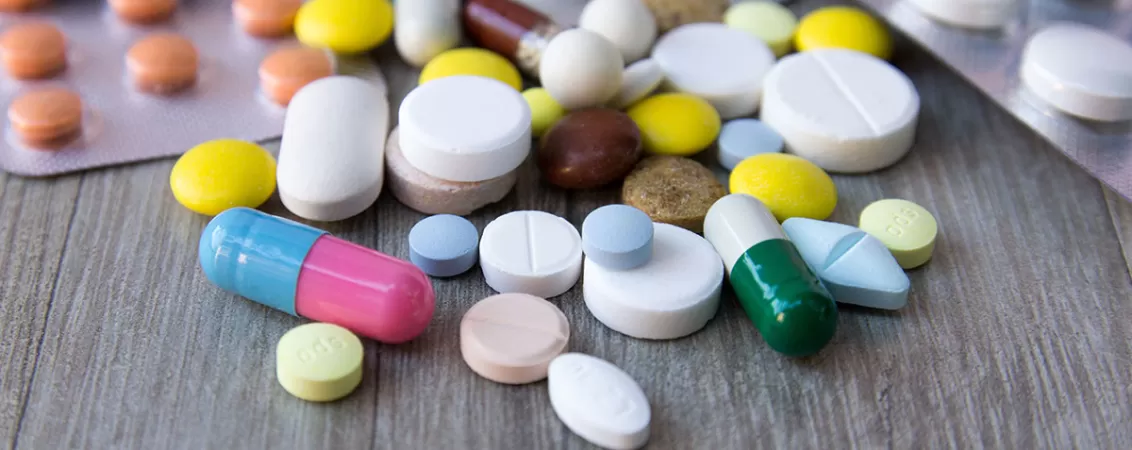 Comprimate si pastile ambalate pe masa, ilustrand produse farmaceutice pentru tratament medical.