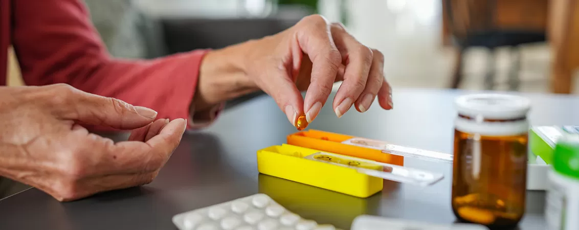 Femei in varsta punand medicamente intr-un organizator.