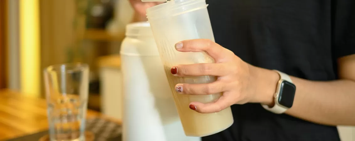 Femeie pregatind un shake cu pudra proteica dupa antrenament