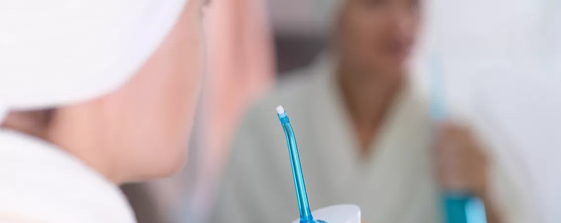 Femeie pregatindu-se sa folosesca un dus bucal dupa baie