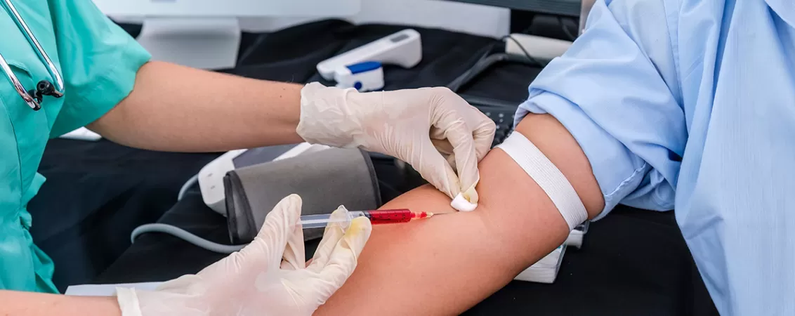 Medic recoltand o proba de sange de la pacient, utilizand echipamente medicale sterile pentru diagnostic si analize clinice.