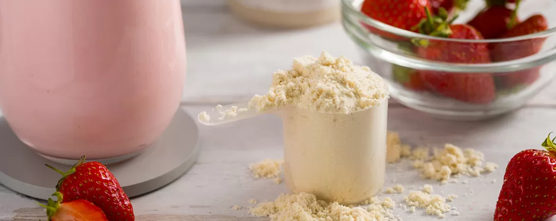 Pudra proteica langa un smoothie cu capsuni