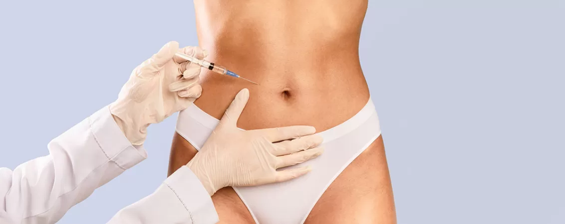 Abdomenul unei femei si mainile unui medic pregatit sa aplica o injectie