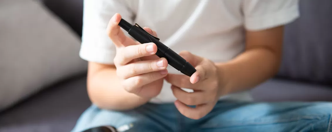 Adolescent isi masoara nivelul glicemiei folosind un glucometru modern