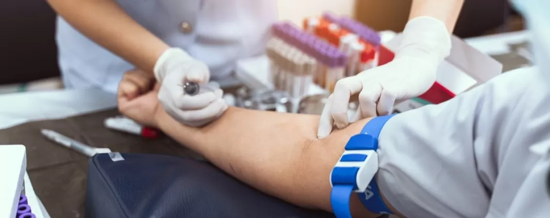 Asistenta medicala preleveaza sange pentru un test de laborator