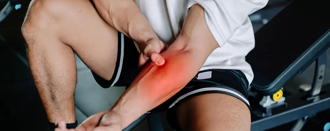 Barbat in sala de sport care sufera de dureri musculare in zona bratului