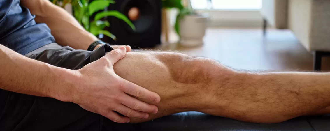 Barbat tinandu-si piciorul din cauza durerii musculare dupa efort fizic