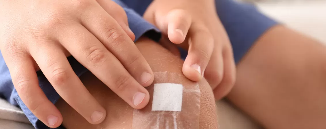 Baiat cu plasture pe genunchi dupa o accidentare usoara la joaca