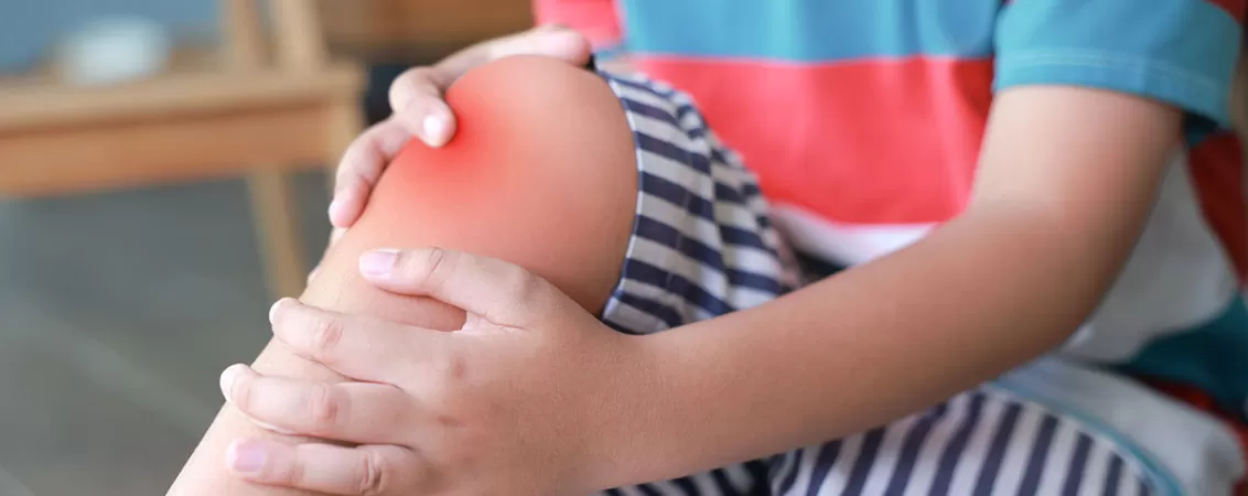 Baietel isi tine genunchiul inflamat din cauza durerii dupa o accidentare