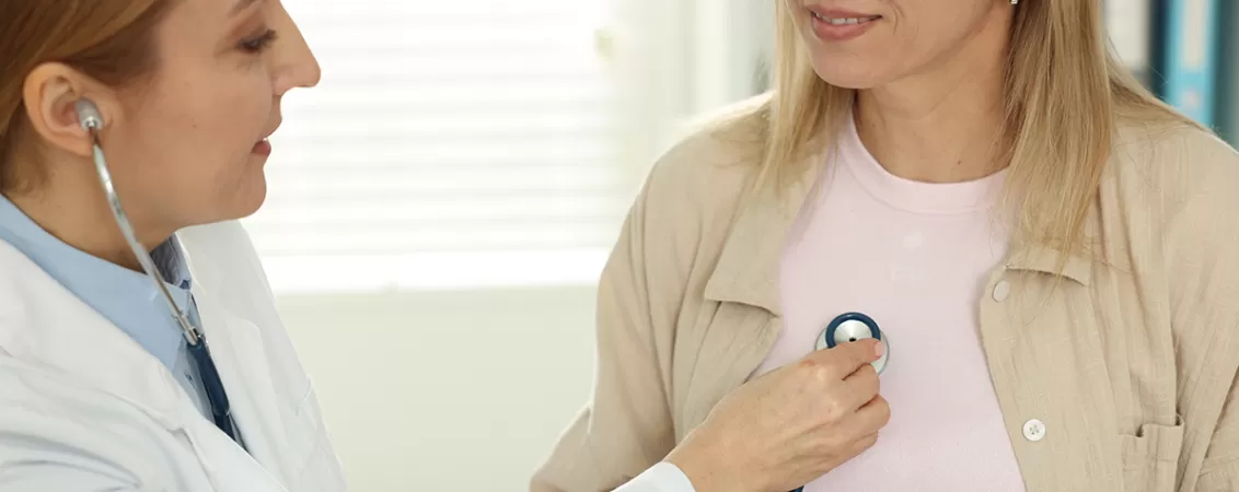 Cardiolog cu stetoscop, ascultand bataile inimii unui pacient la o masa din cabinet