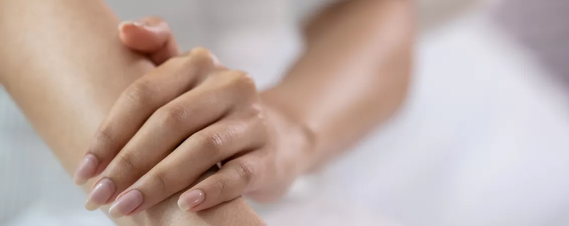 Femeie acoperindu-si bratul cu mana opusa.