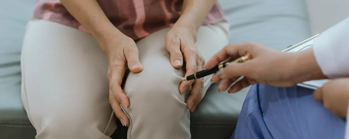 Medic examineaza un pacient cu durere de genunchi