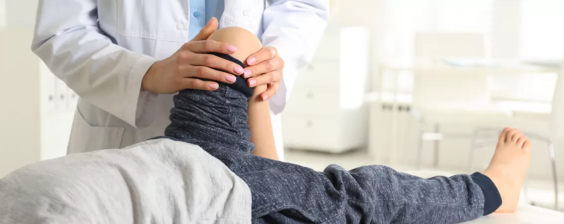 Medic ortoped care examineaza piciorul unui copil