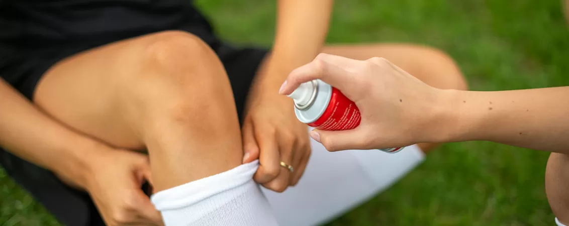 Persoana aplica un spray pentru calmarea durerii la nivelul genunchiului